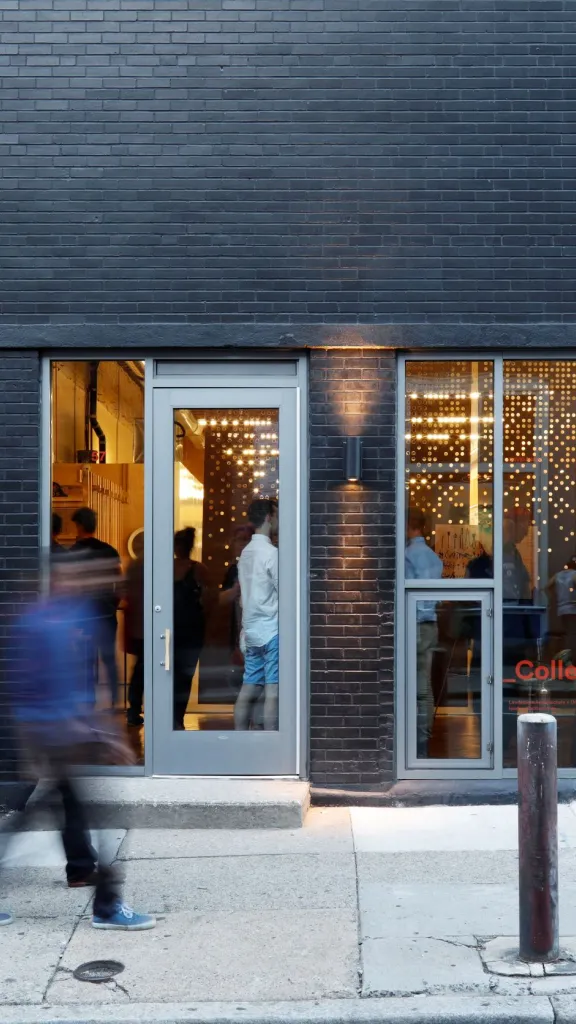 A picture of the GALLERY Land Collective façade with motion-blurred people walking in front of it.