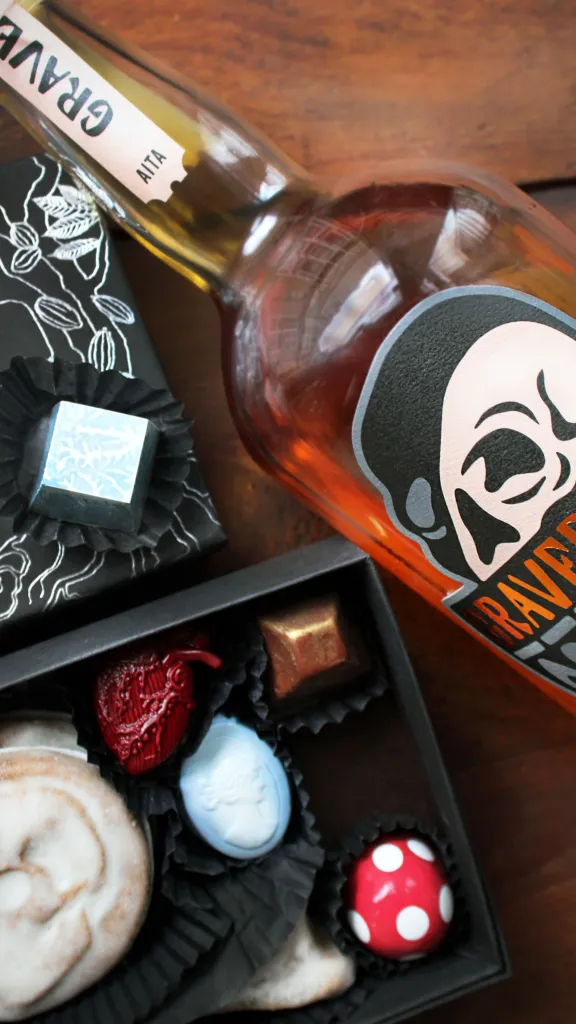 A bottle of Graverobber Unholy Rye Whiskey and a box of specialty chocolates