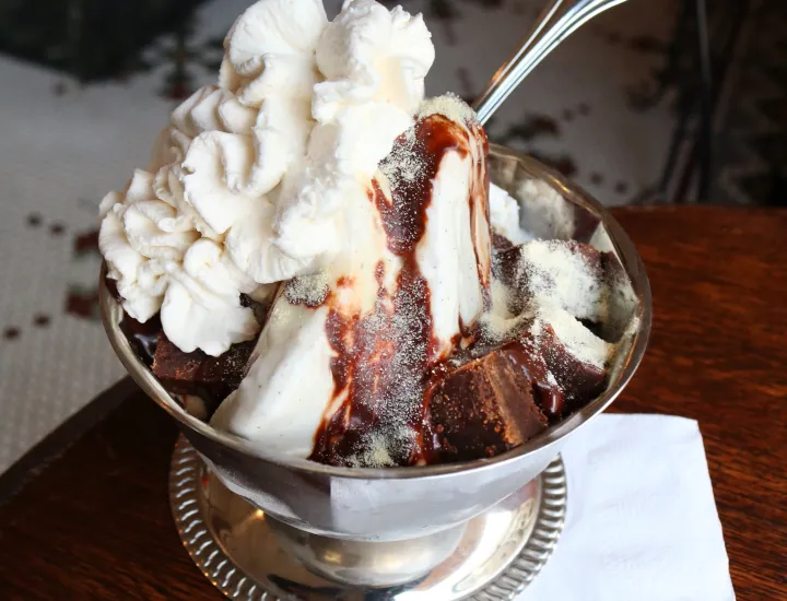 Ice cream sundae with whipped cream in silver dish on counter at The Franklin Fountain