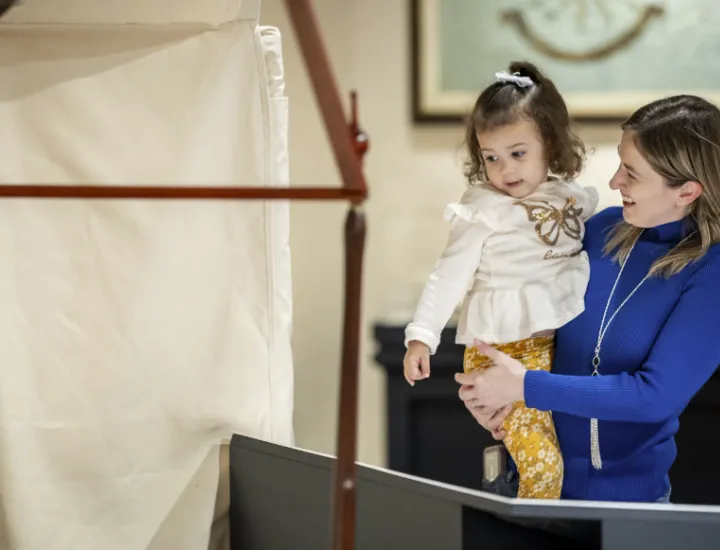 Woman holding child looking at display in Witness to Revolution special exhibit.