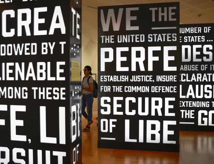 woman walking through signs with words of the Preamble of the Constitution