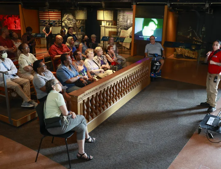 person presenting in front of tv to crowd